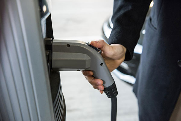 Man charging an electric vehicle at a public station